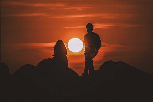 human silhouette of two people looking at sunset person