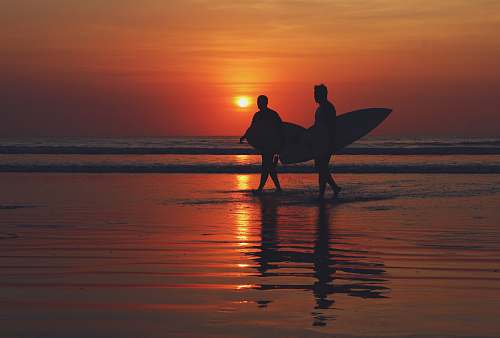 bali silhouette of two people walking on seashore during sunset indonesia