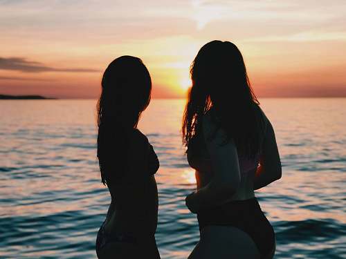 person silhouette of two women looking at sunset human