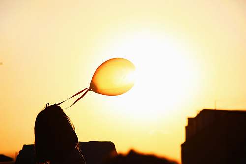 sunset silhouette of woman holding balloon sky