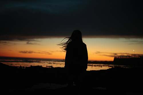 sky silhouette of woman near beach sunset