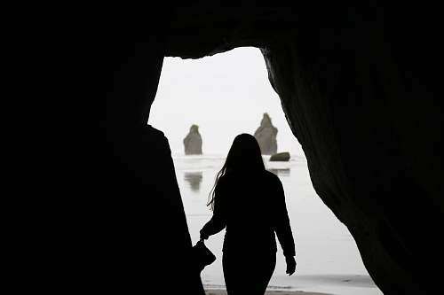 nature silhouette of woman near the cave shoreline