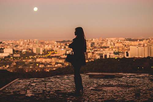 person silhouette of woman standing during golden hour photography lisbon