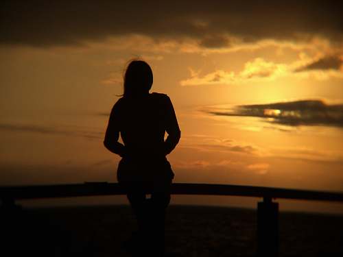 human silhouette of woman standing near beach line person