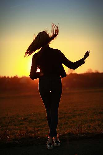 human silhouette of woman standing near grass field person