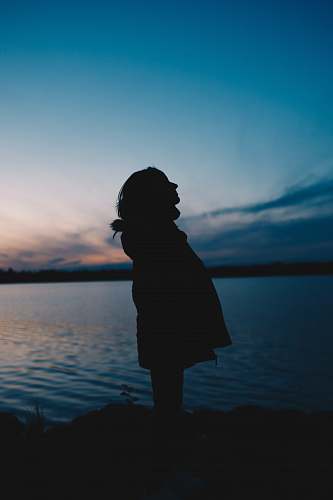 water silhouette of woman standing on seashore outdoors