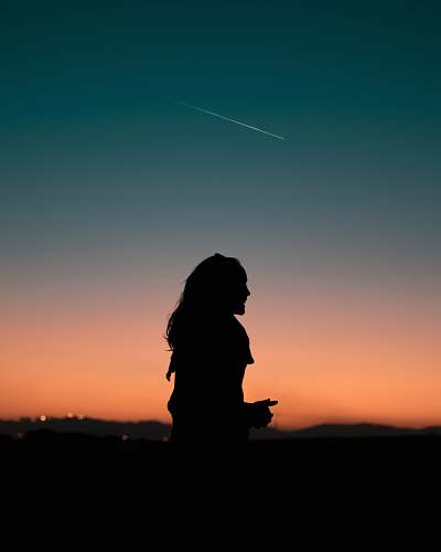 person silhouette of woman standing under blue sky during golden hour people