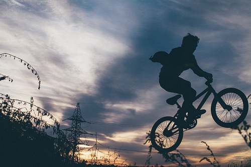 bike silhouette photo of bikers showing exhibition on air during orange sunset bmx