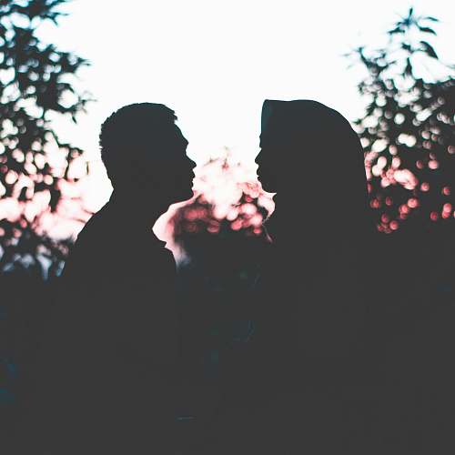 light silhouette photo of man and woman facing each other flare