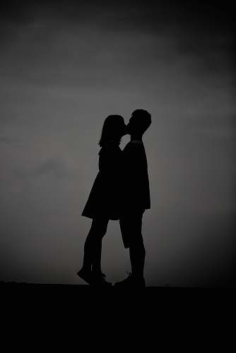 black-and-white silhouette photo of man and woman kissing grey