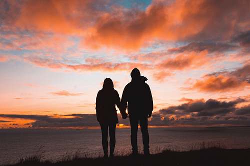 person silhouette photo of man and woman on cliff people
