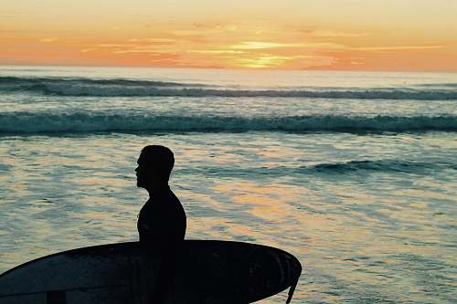 human silhouette photo of man holding surfboard person