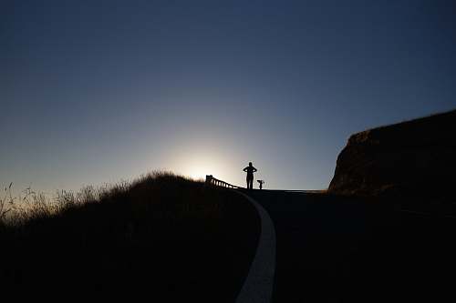 person silhouette photo of person above hill grass