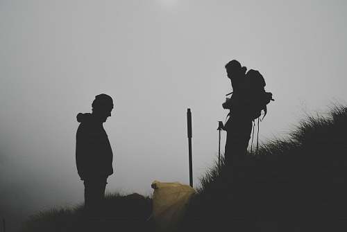 human silhouette photo of two men climbing mountain people
