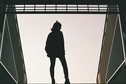 human silhouette photo of woman standing on concrete road people