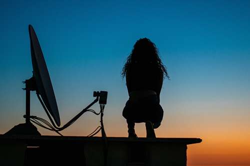 human silhouette photo of woman standing on top of building person