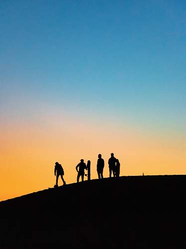 human silhouette photography of four people holding snowboards person