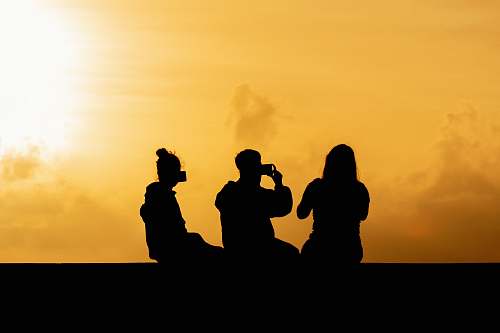 human silhouette photography of man sitting beside two women person