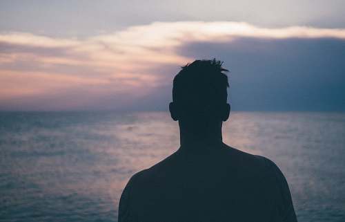 person silhouette photography of man standing near sea human