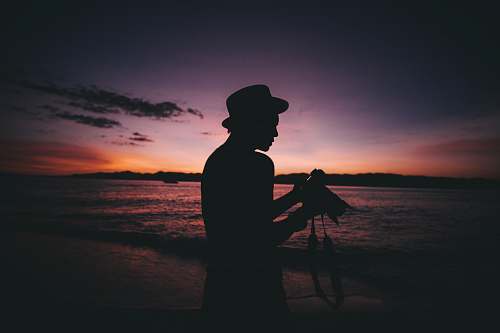 human silhouette photography of man standing while holding DSLR camera person