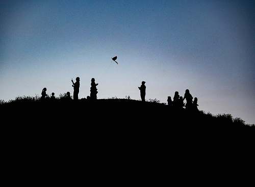 outdoors silhouette photography of people on top of a land formation animal
