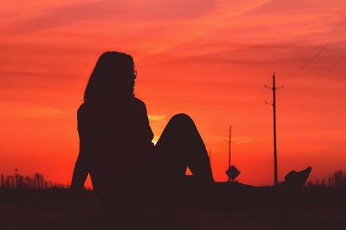 nature silhouette photography of person sitting on grass outdoors
