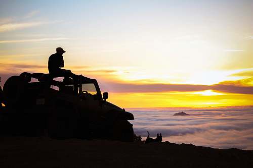 human silhouette photography of person sitting on truck person
