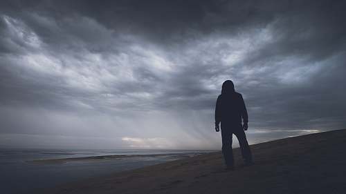 person silhouette photography of person under gray clouds grey
