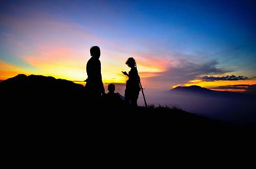 human silhouette photography of three persons on mountain during golden hour person