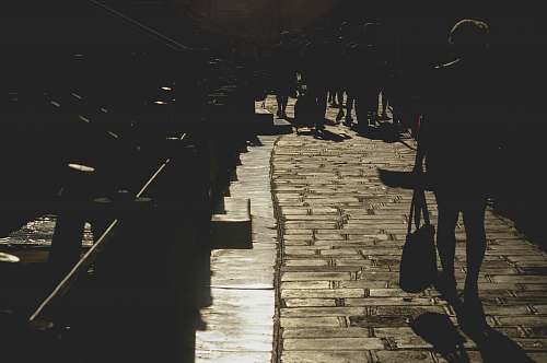 people silhouette photography of woman passing through bridge dock