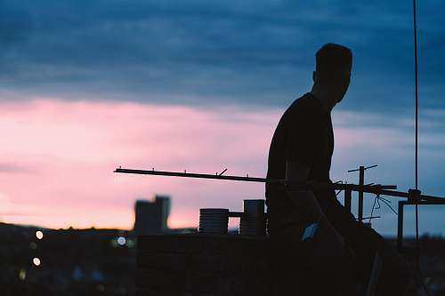 human silhouette view of man sits on higher ground outdoors