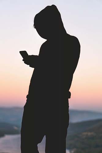 human silhoutte of person using smartphone person