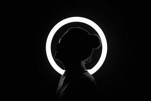 person woman standing beside halo light black-and-white