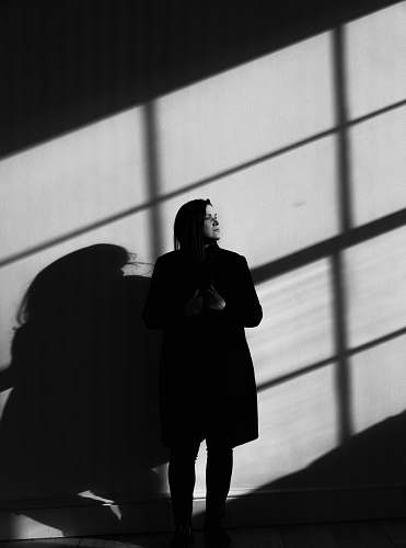 black-and-white woman standing near wall grey