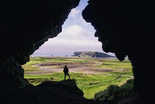 iceland woman standing on rock formation during daytimr dyrhólaey