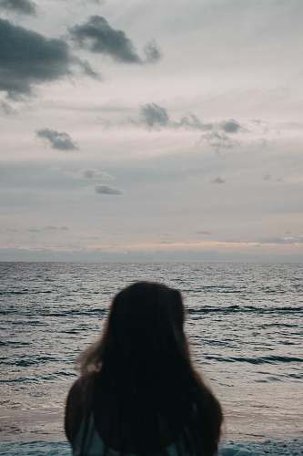 nature woman wearing white top standing near ocean grey