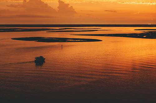 sunrise aerial photo of calm water near islands sunset