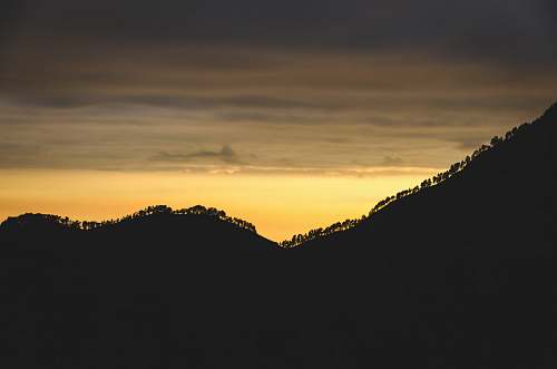 sunset silhouette of mountain with trees trees