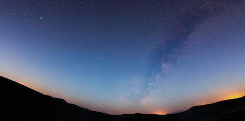 stars silhouette photo of mountain celestial