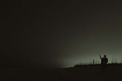 black silhouette of two people looking at stars night sky
