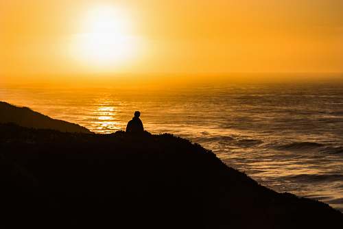 sunset silhouette photography of man walking hill