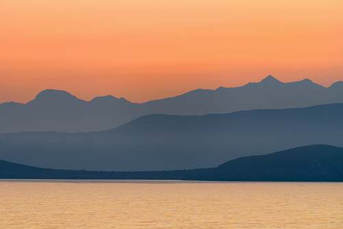 sunset silhouette of mountains near body of water during golden hour greece