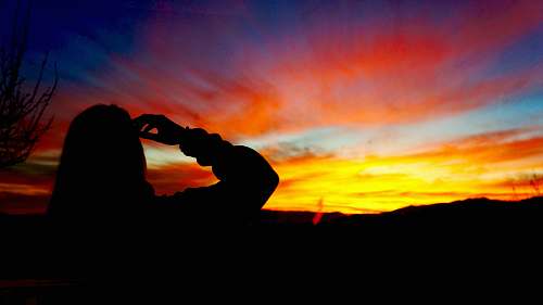 sunset silhouette of person facing mountain during golden hour silhouette