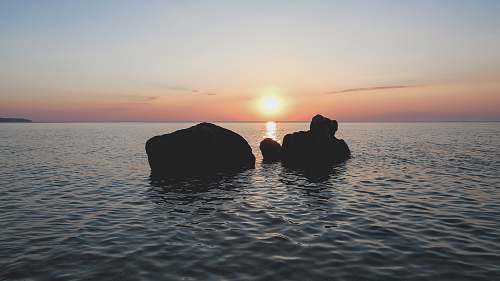 greece silhouette of rocks on body of water during golden hour rocks