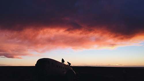 sunrise two person standing on white airplane solheimasandur