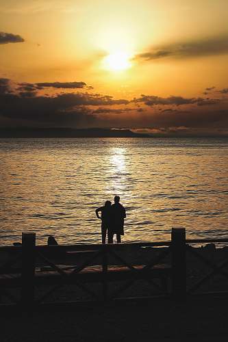 human silhouette of couple standing near sea person