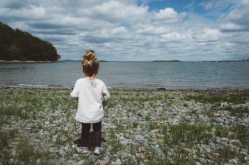  girl standing on seashore during daytime 