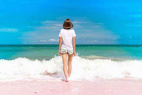 water time lapse photography of woman standing in front of sea waves person