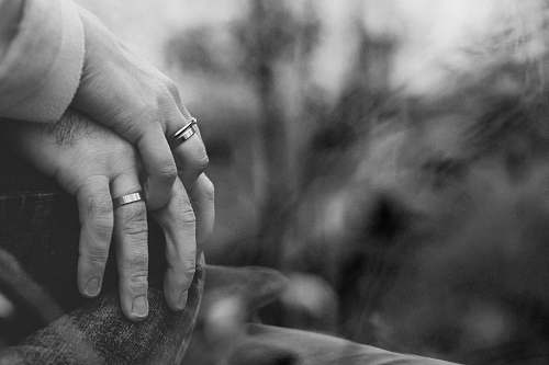 grey grayscale photo of two person holding hands with wedding rings ring