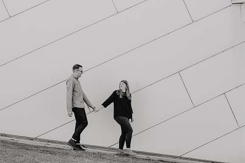 human grayscale photo of woman holding hand of man people